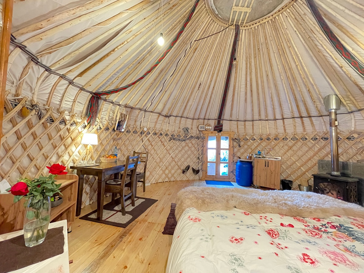 Interior of the yurt with wood stove, bed and dining table