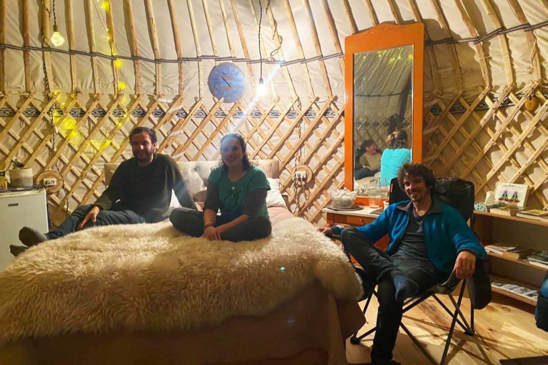 Guests and hosts sitting together inside the yurt in the evening